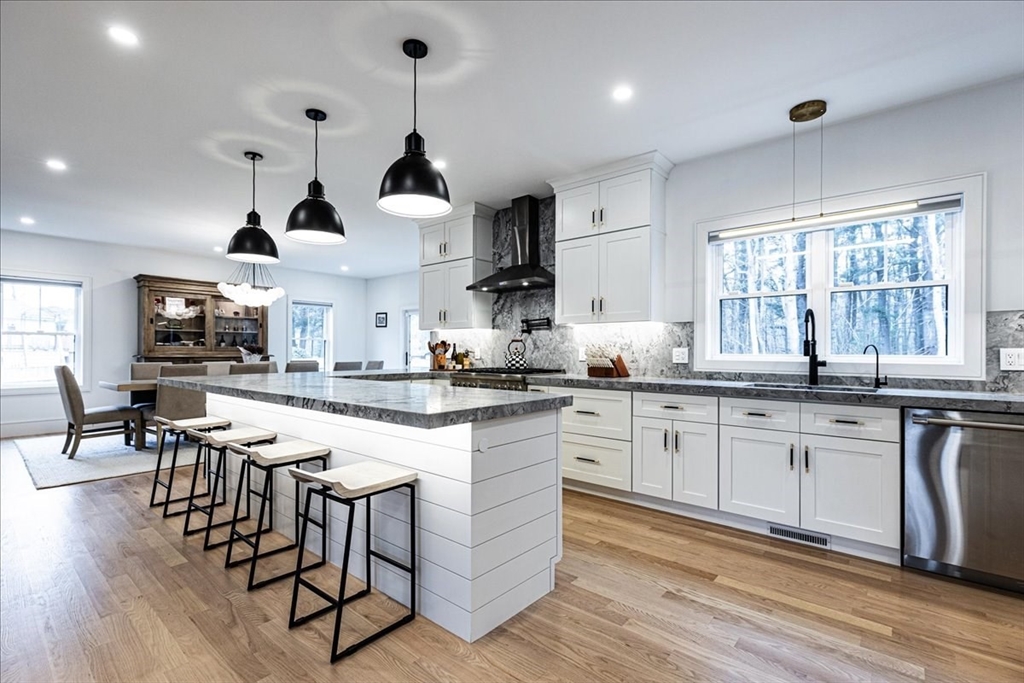 5 Brookside Lane Burlington, MA 01803 - Photo 11 of 42 a kitchen with stainless steel appliances granite countertop a stove a sink dishwasher a dining table and chairs with wooden floor