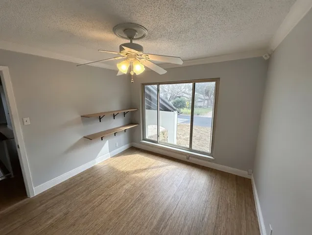 an empty room with wooden floor fan and windows