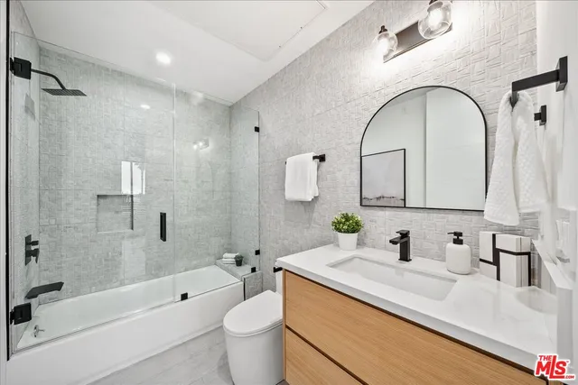 a bathroom with a granite countertop sink a toilet and shower