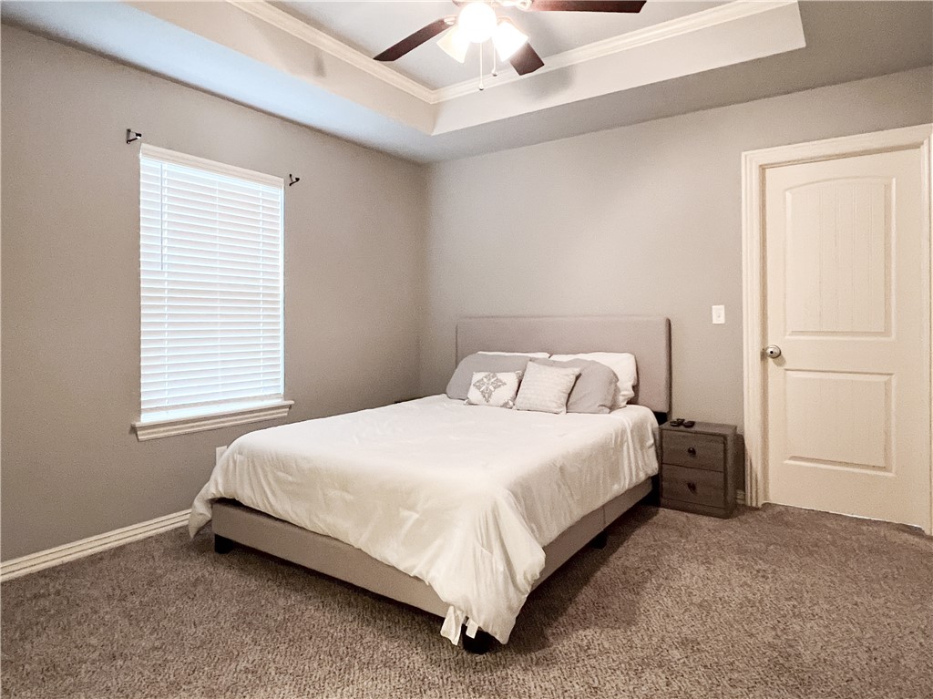 1275 North Rupple Road Fayetteville, AR 72704 - Photo 17 of 20 Bedroom with tray ceiling, crown molding, a ceiling fan, carpet flooring, and a white paneled door