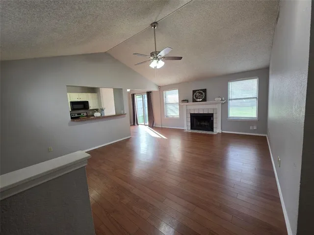 an empty room with wooden floor fireplace and windows
