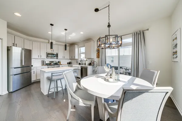 a kitchen with stainless steel appliances kitchen island granite countertop a dining table chairs and white cabinets
