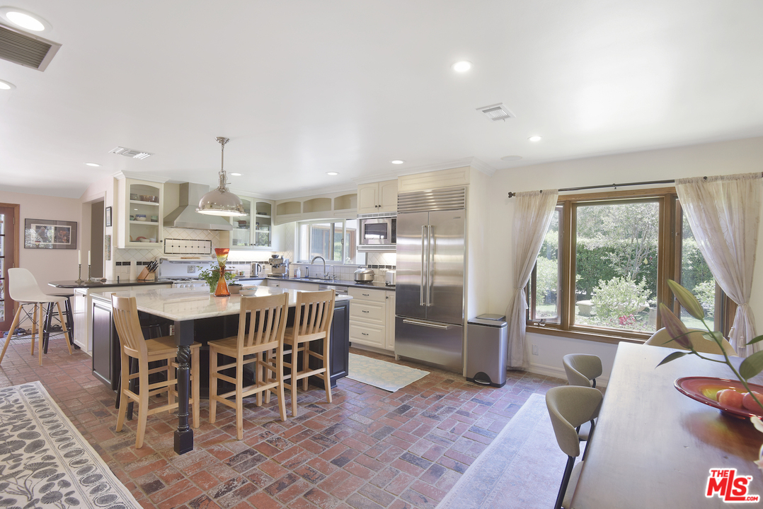 6138 Ramirez Canyon Road Malibu, CA 90265 - Photo 12 of 42 a dining area with stainless steel appliances a table and chairs