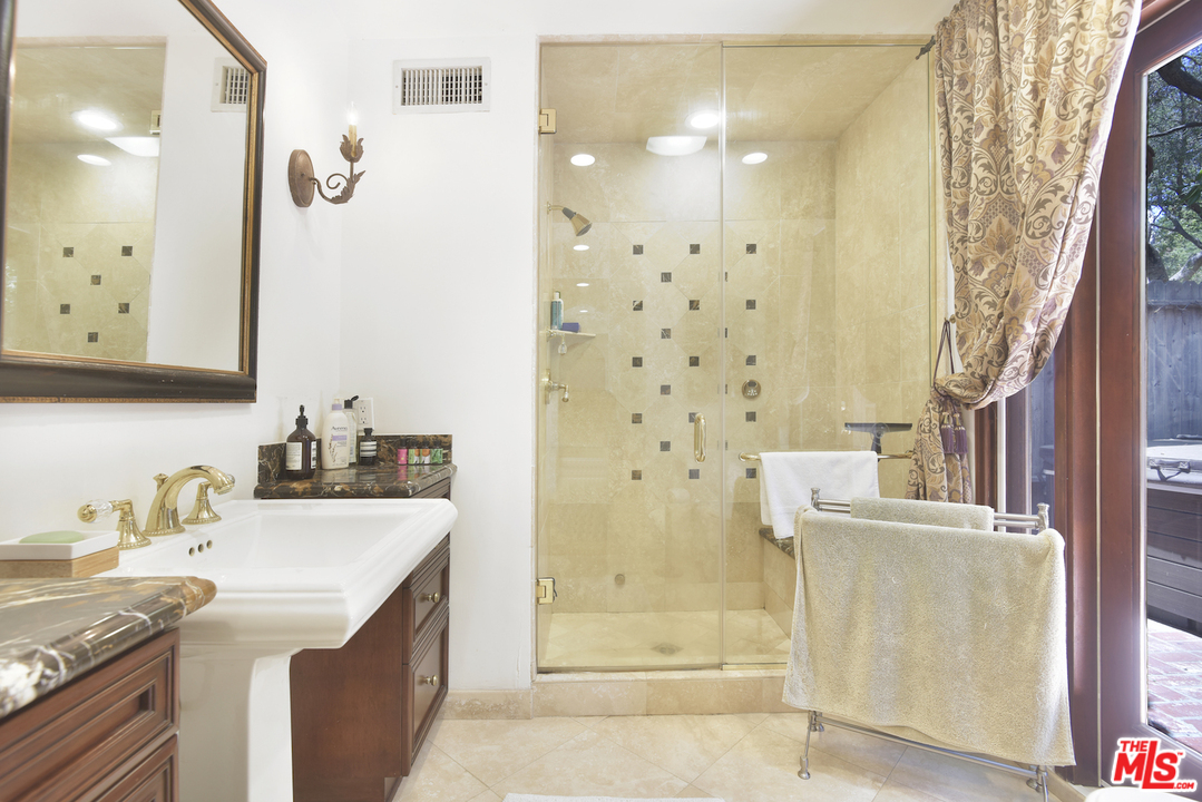 6138 Ramirez Canyon Road Malibu, CA 90265 - Photo 28 of 42 a bathroom with a granite countertop sink a mirror a shower and vanity