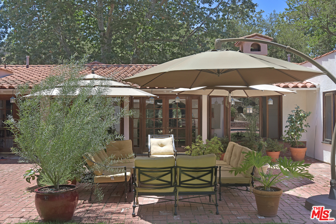 6138 Ramirez Canyon Road Malibu, CA 90265 - Photo 38 of 42 a patio with tables and chairs and a umbrella