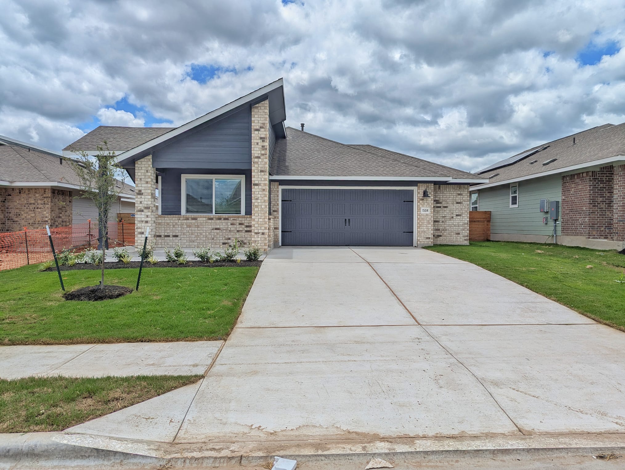 Mid-century home with brick siding, a garage, driveway, and roof with shingles