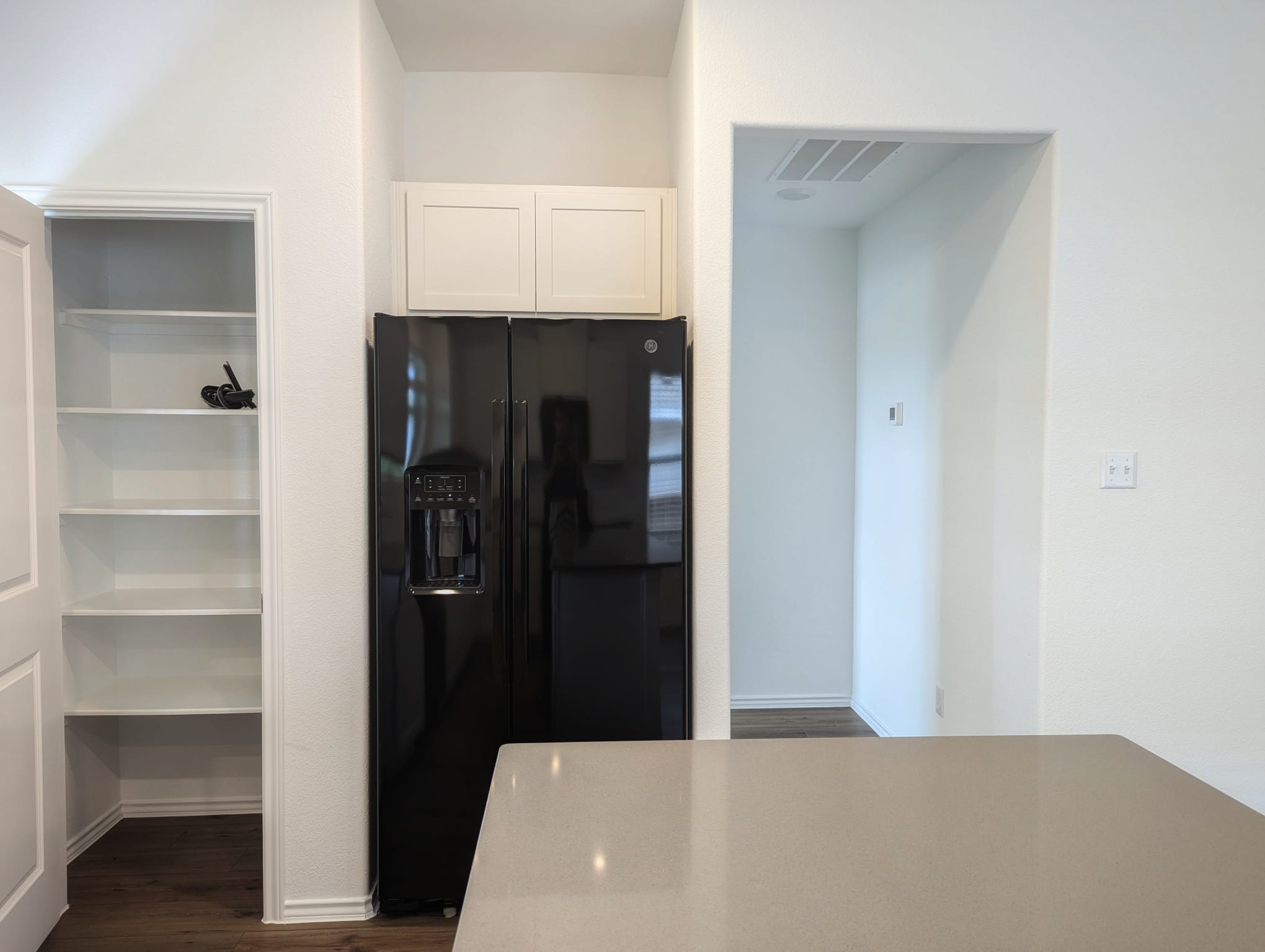 1504 Marley Kyle, TX 78640 - Photo 11 of 28 Kitchen with black refrigerator with ice dispenser, dark wood-style floors, and white cabinets