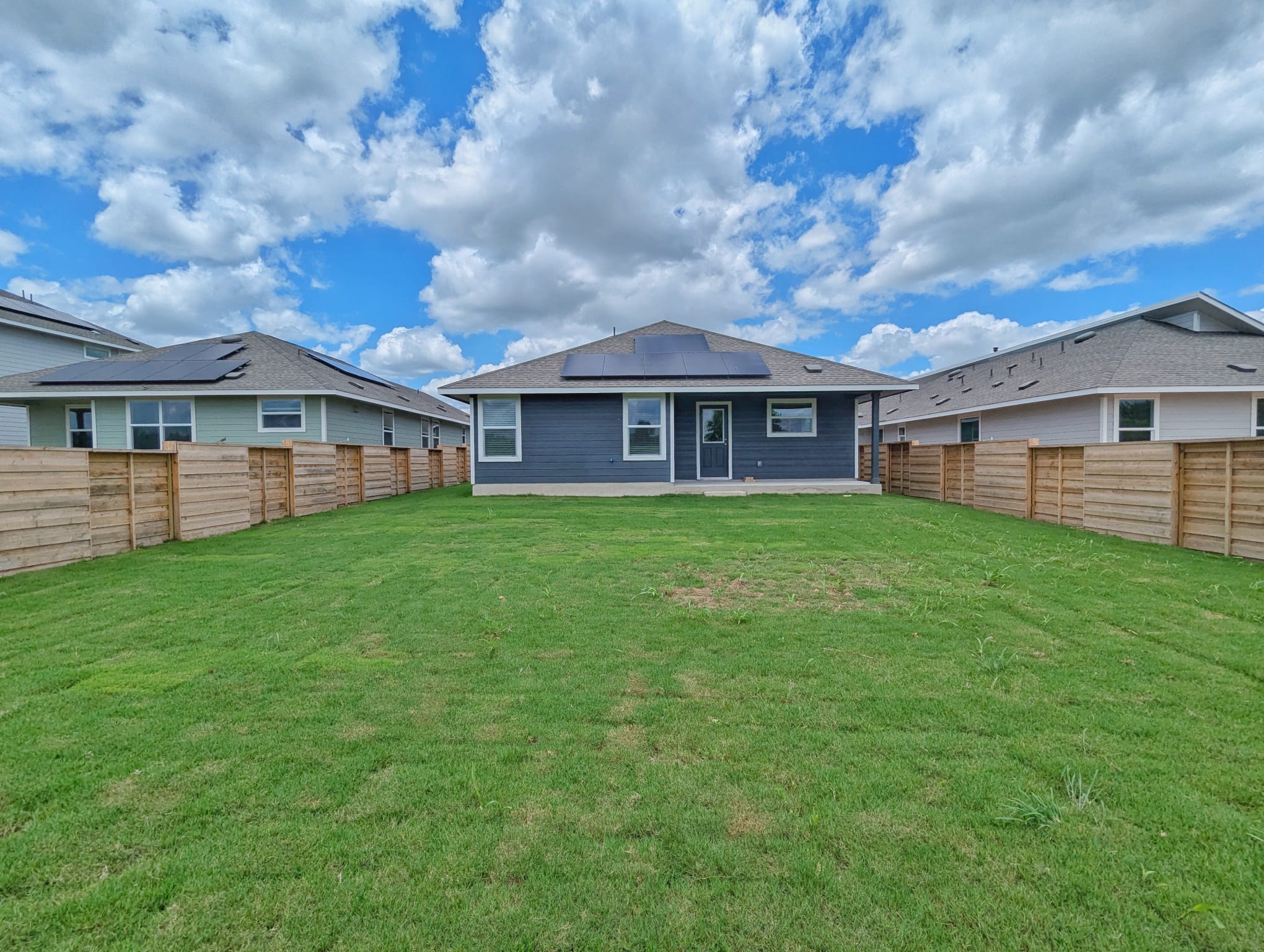 1504 Marley Kyle, TX 78640 - Photo 24 of 28 Back of house featuring roof mounted solar panels, a fenced backyard, and a patio area