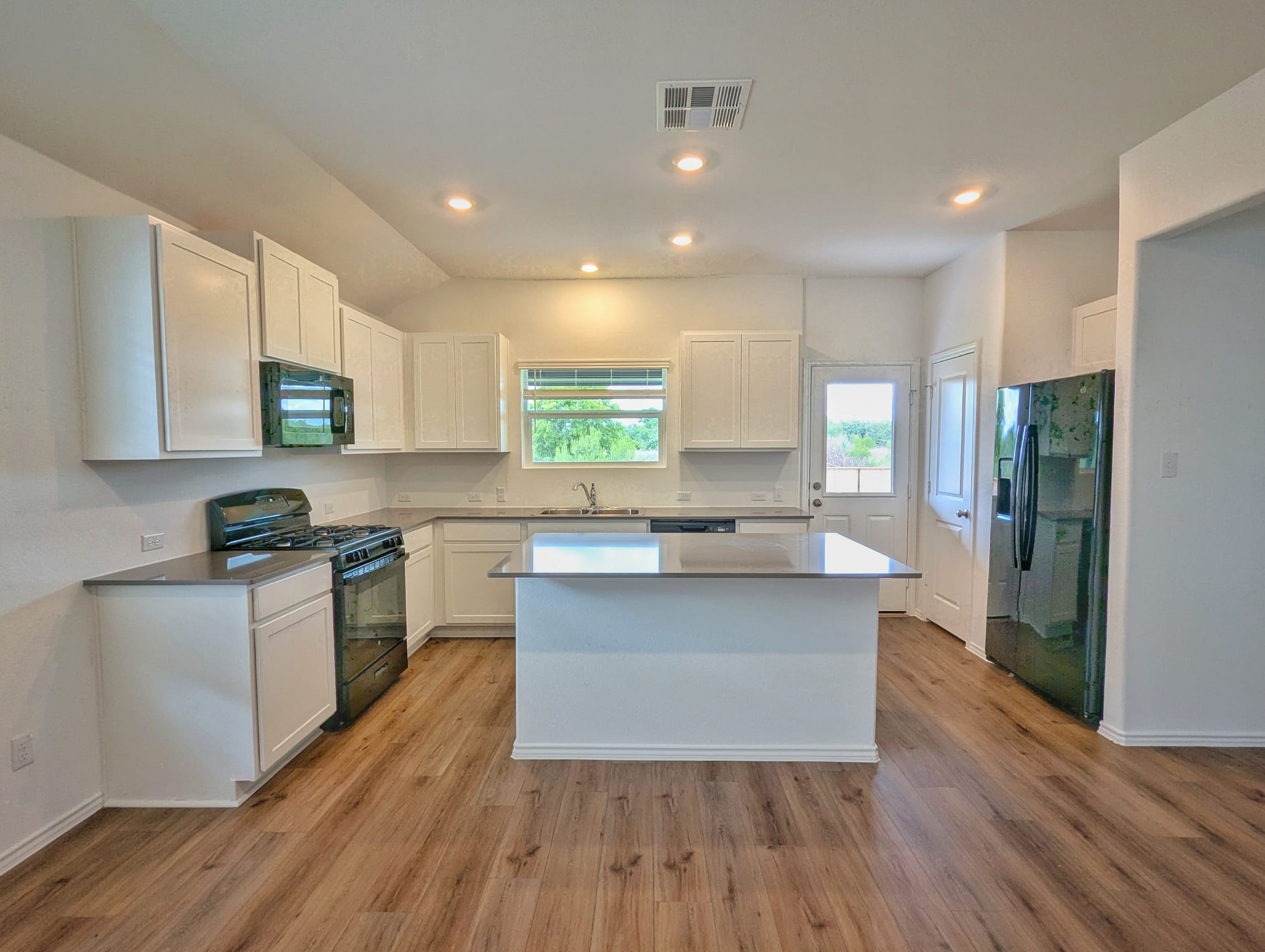 1504 Marley Kyle, TX 78640 - Photo 4 of 28 Kitchen with black appliances, white cabinets, a kitchen island, recessed lighting, and light wood-style floors