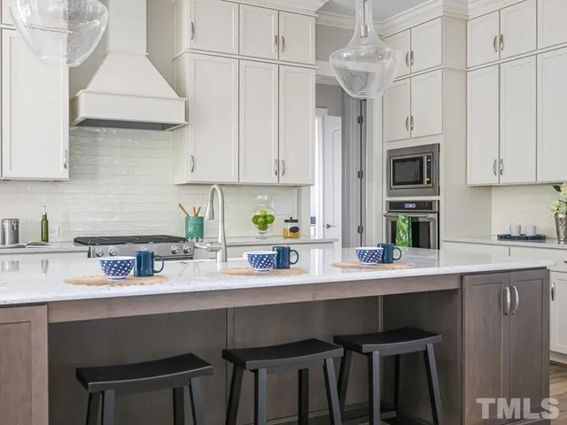 a kitchen with stainless steel appliances a table chairs in it and white cabinets