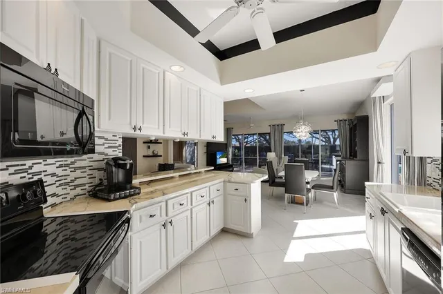 a kitchen with stainless steel appliances granite countertop a sink a stove top oven a refrigerator with white cabinets and a refrigerator