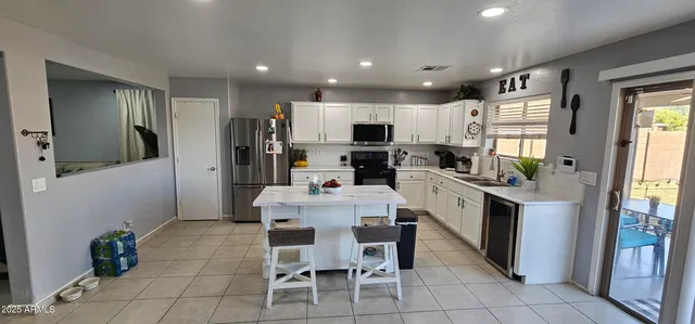 a kitchen with kitchen island granite countertop stainless steel appliances a sink a counter top space cabinets and a dining table