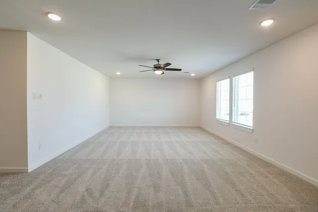 an empty room with a ceiling fan and window