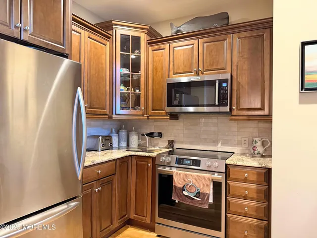 a kitchen with stainless steel appliances granite countertop a refrigerator a stove a sink and a microwave