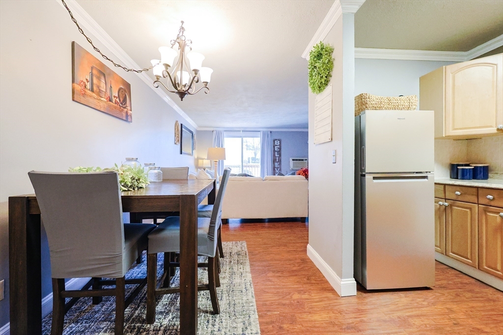 116 Boston Post Road East, Unit 101 Marlborough, MA 01752 - Photo 4 of 34 a kitchen with stainless steel appliances granite countertop a refrigerator a stove a sink dishwasher and a dining table with wooden floor
