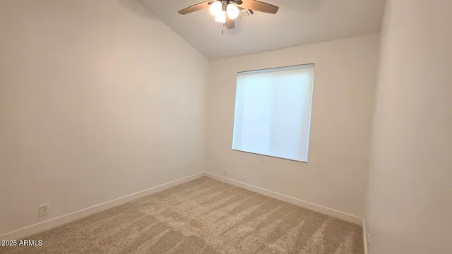 an empty room with a chandelier fan and windows