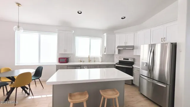 a kitchen with a dining table chairs and refrigerator