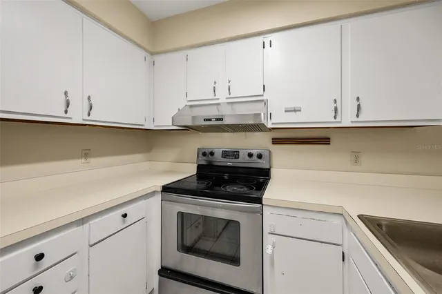 a kitchen with granite countertop white cabinets and a stove