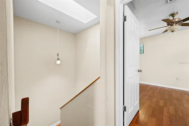 a view of empty room with wooden floor and fan