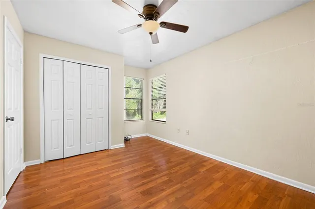 a view of a room with wooden floor and a ceiling fan