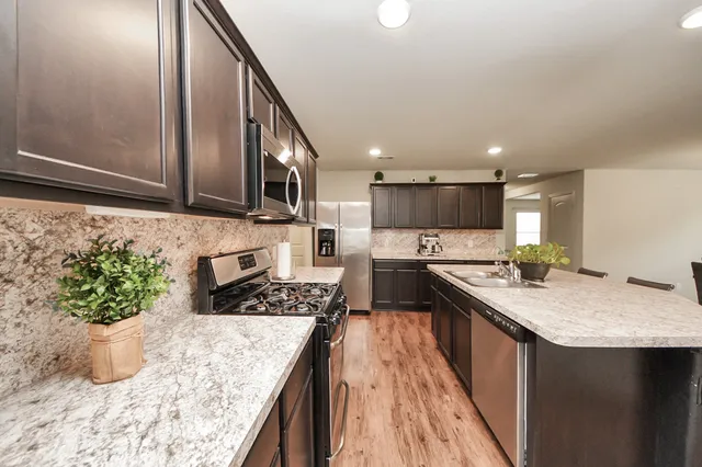 a kitchen with stainless steel appliances granite countertop a sink stove and refrigerator
