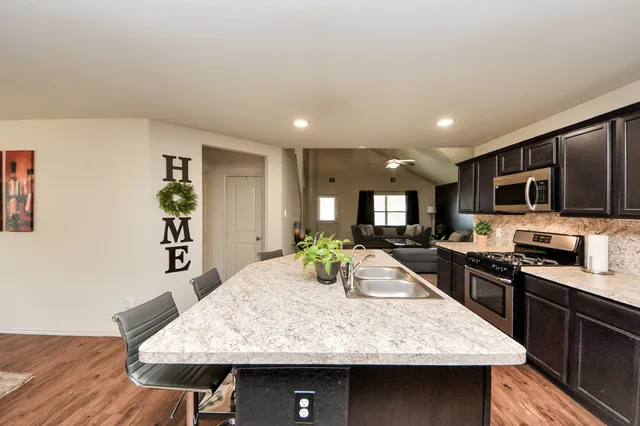 a kitchen with kitchen island stainless steel appliances and wooden cabinets