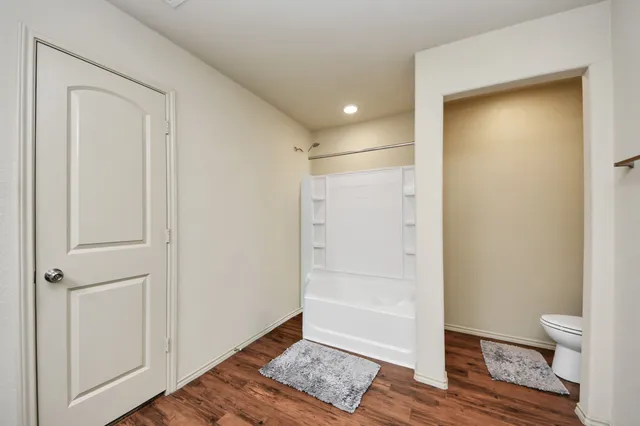 a view of room with wooden floor and bathroom view