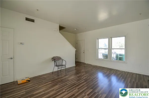 a view of an empty room with wooden floor and window