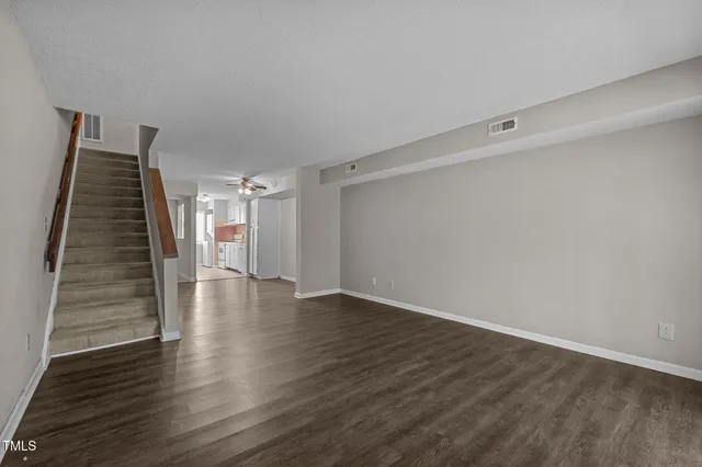 a view of an empty room with wooden floor and stairs