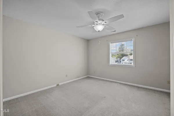 an empty room with a chandelier fan and windows
