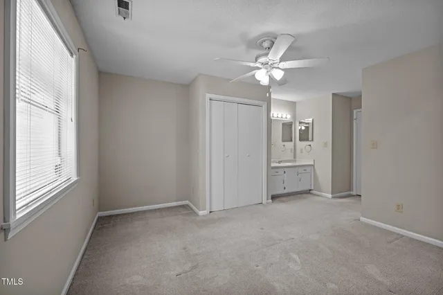 an empty room with a chandelier fan and windows