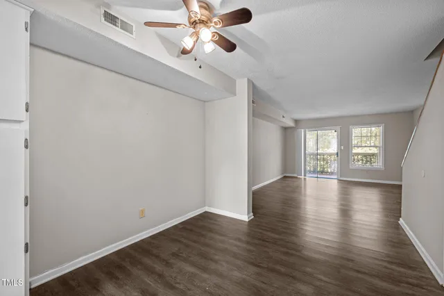 a view of empty room with wooden floor and fan