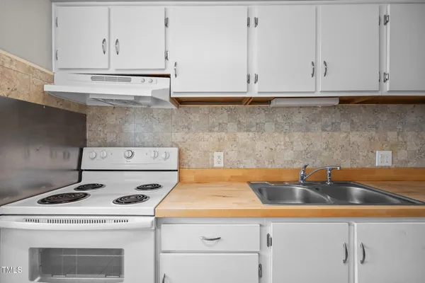 a kitchen with a stove and white cabinets