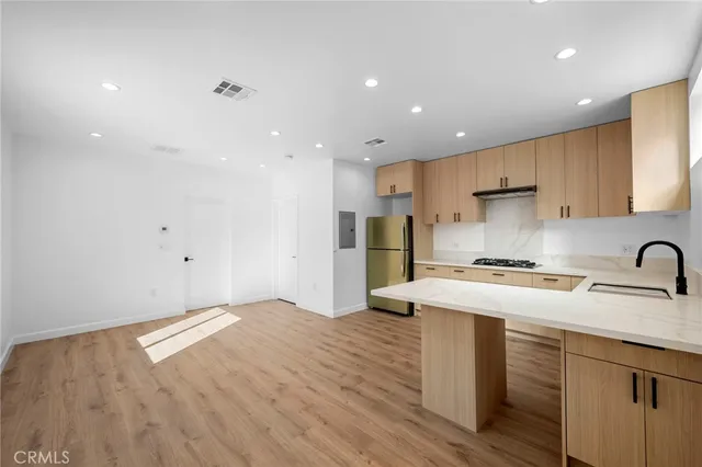 a kitchen with stainless steel appliances granite countertop a sink a stove a refrigerator and cabinets