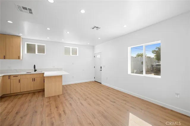 a large white kitchen with sink and dishwasher with wooden floor