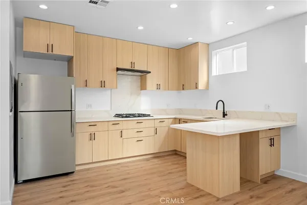 a kitchen with a sink a refrigerator a stove and white cabinets with wooden floor