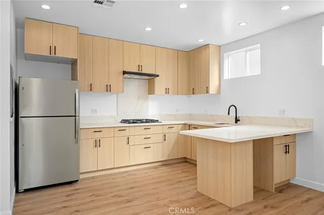 a kitchen with a sink a refrigerator a stove and white cabinets with wooden floor