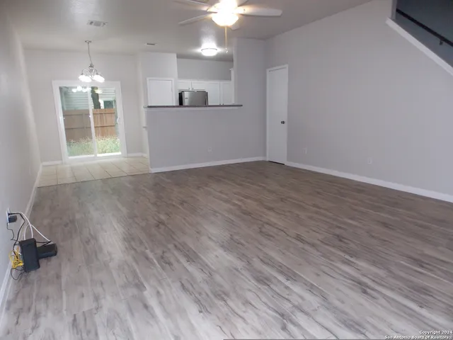 a view of empty room with wooden floor and kitchen view