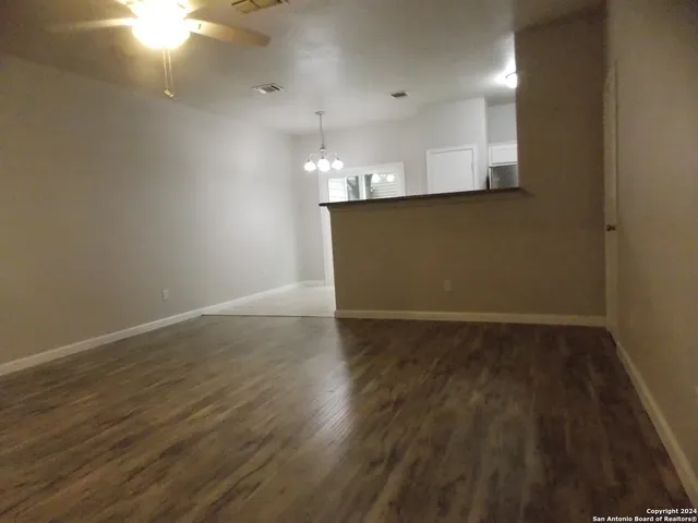 a view of kitchen and empty room with wooden floor