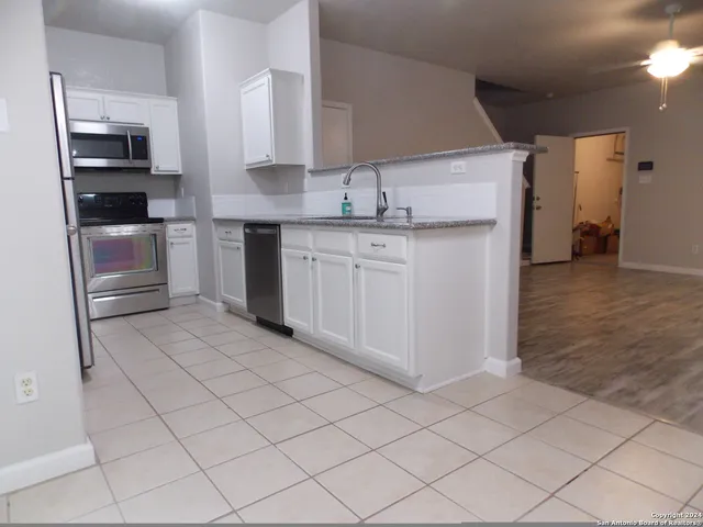 a kitchen with white cabinets and appliances