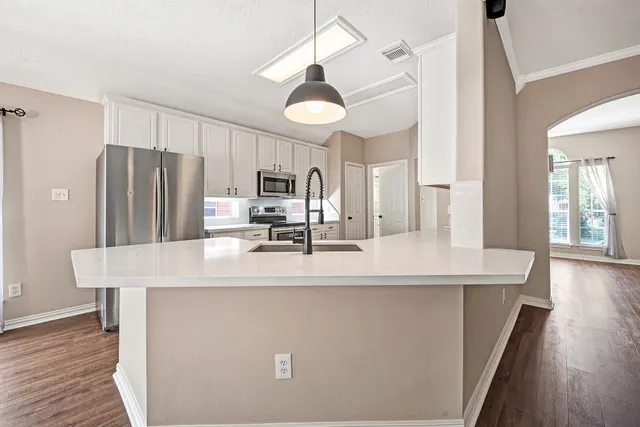 a kitchen with kitchen island a counter top space a refrigerator a stove a chimney cabinets and wooden floor