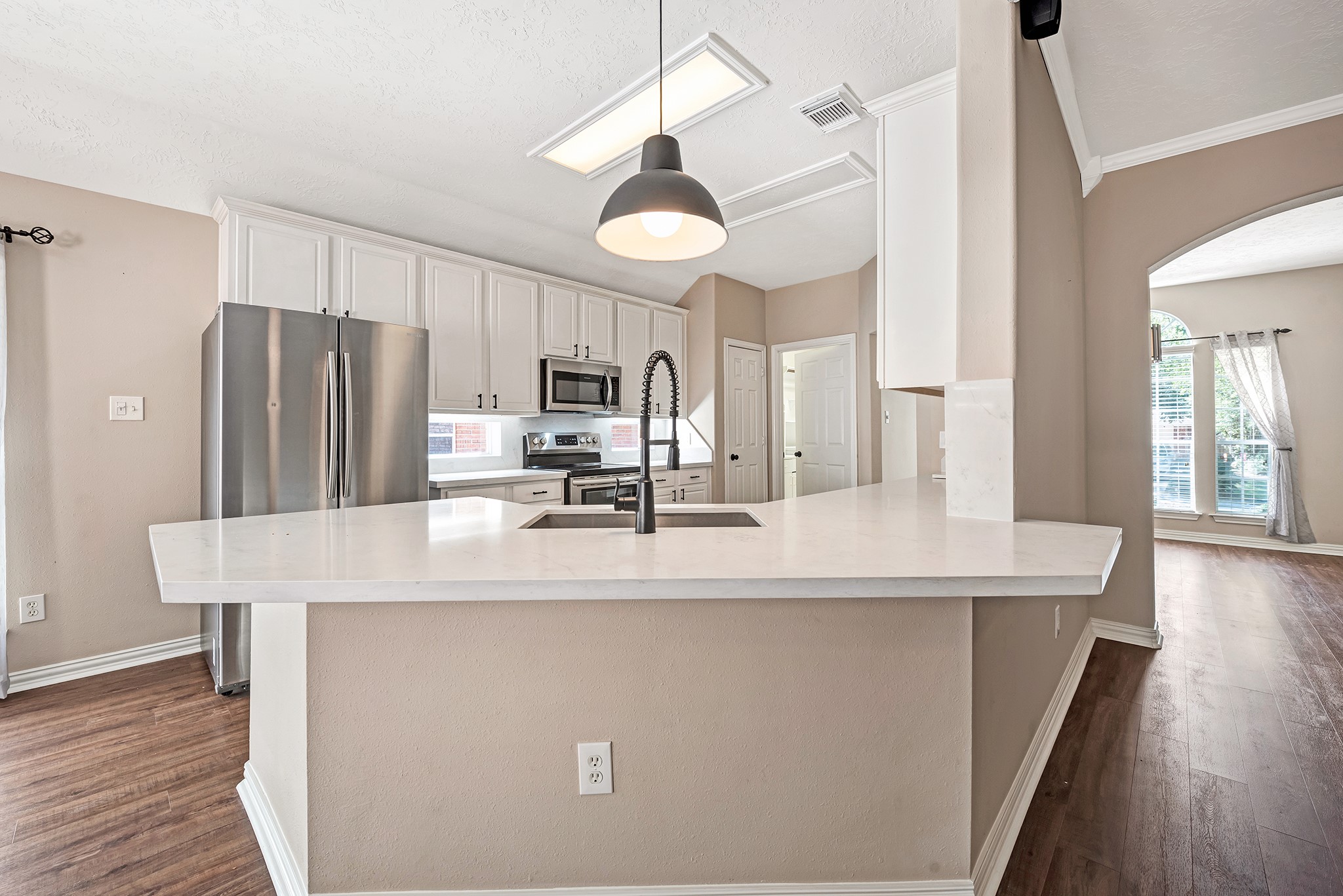 135 West Russet Grove Circle The Woodlands, TX 77384 - Photo 14 of 31 a kitchen with kitchen island a counter top space a refrigerator a stove a chimney cabinets and wooden floor