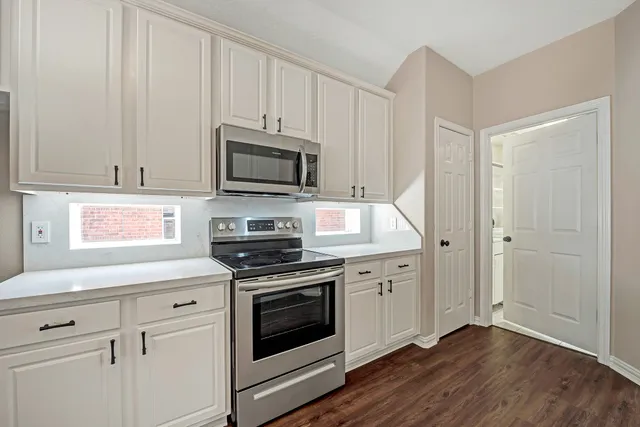 a kitchen with cabinets stainless steel appliances and wooden floor