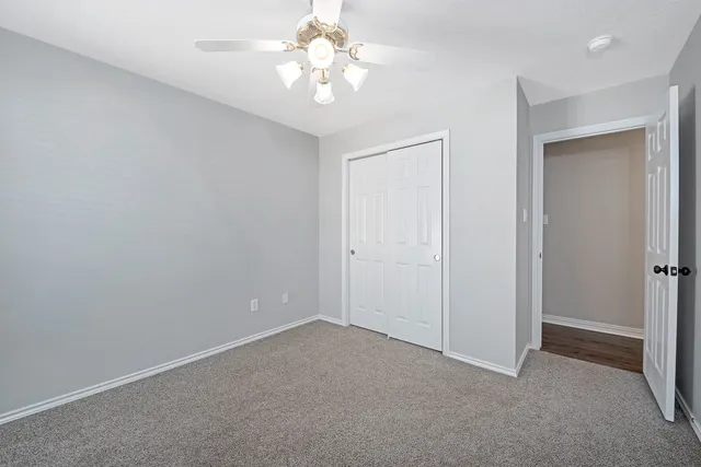 an empty room with a chandelier fan and closet