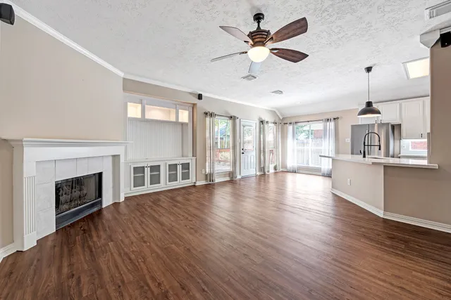 a view of an empty room with wooden floor and a fireplace