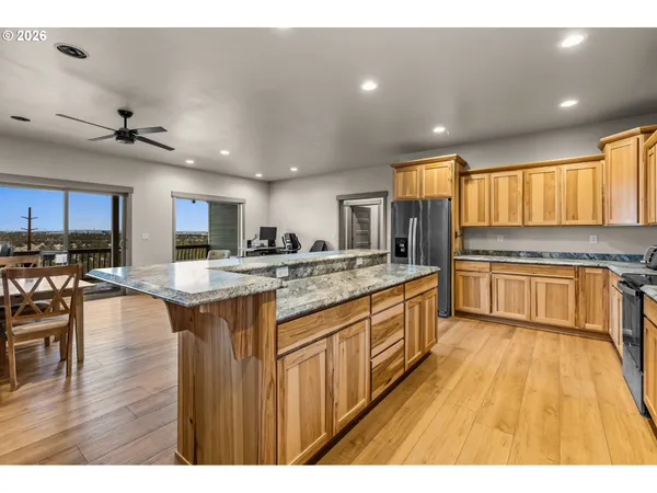a kitchen with stainless steel appliances granite countertop wooden cabinets a sink a stove a kitchen island and chairs