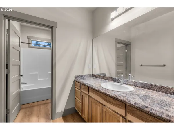 a bathroom with a granite countertop sink a mirror and a bathtub