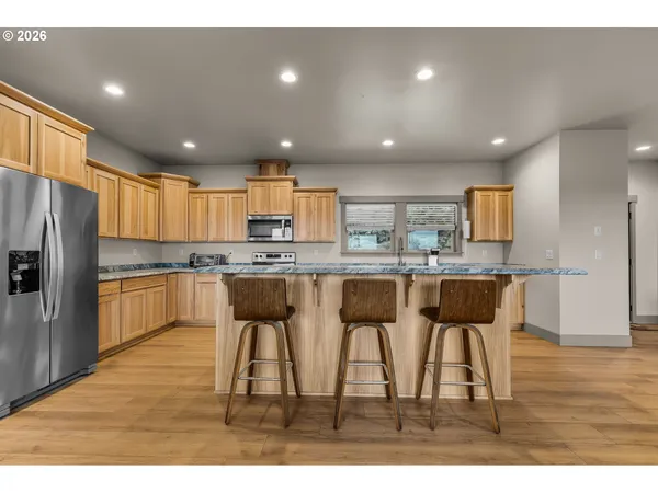 a kitchen with stainless steel appliances kitchen island granite countertop a refrigerator and a stove top oven