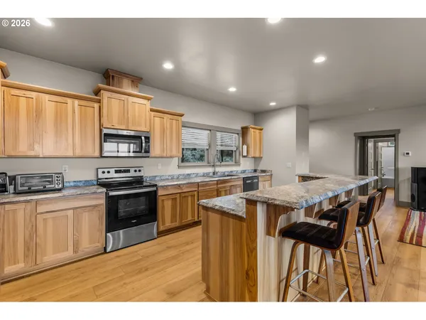 a kitchen with stainless steel appliances kitchen island granite countertop a table chairs sink and cabinets