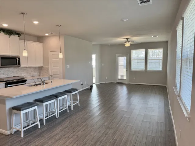 a large kitchen with kitchen island a stove a sink dishwasher and a oven with wooden floor